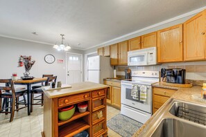 A kitchen with wooden cabinets, a white refrigerator, a microwave, and a stove.