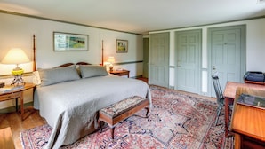 A bedroom with a bed, bedside tables, a bench, a rug, and two doors.