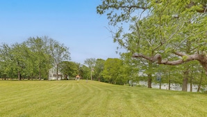 A grassy field with trees and a white building in the background.