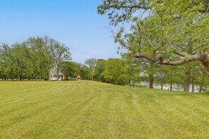 A grassy field with trees and a white building in the background. - Private, Exclusive, Colonial Pocomoke River Estate (Pocomoke City)