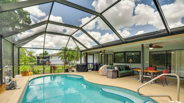Ein überdachter Swimmingpool mit Glasdach, eine Lounge-Bereich mit Möbeln und Blick ins Freie.