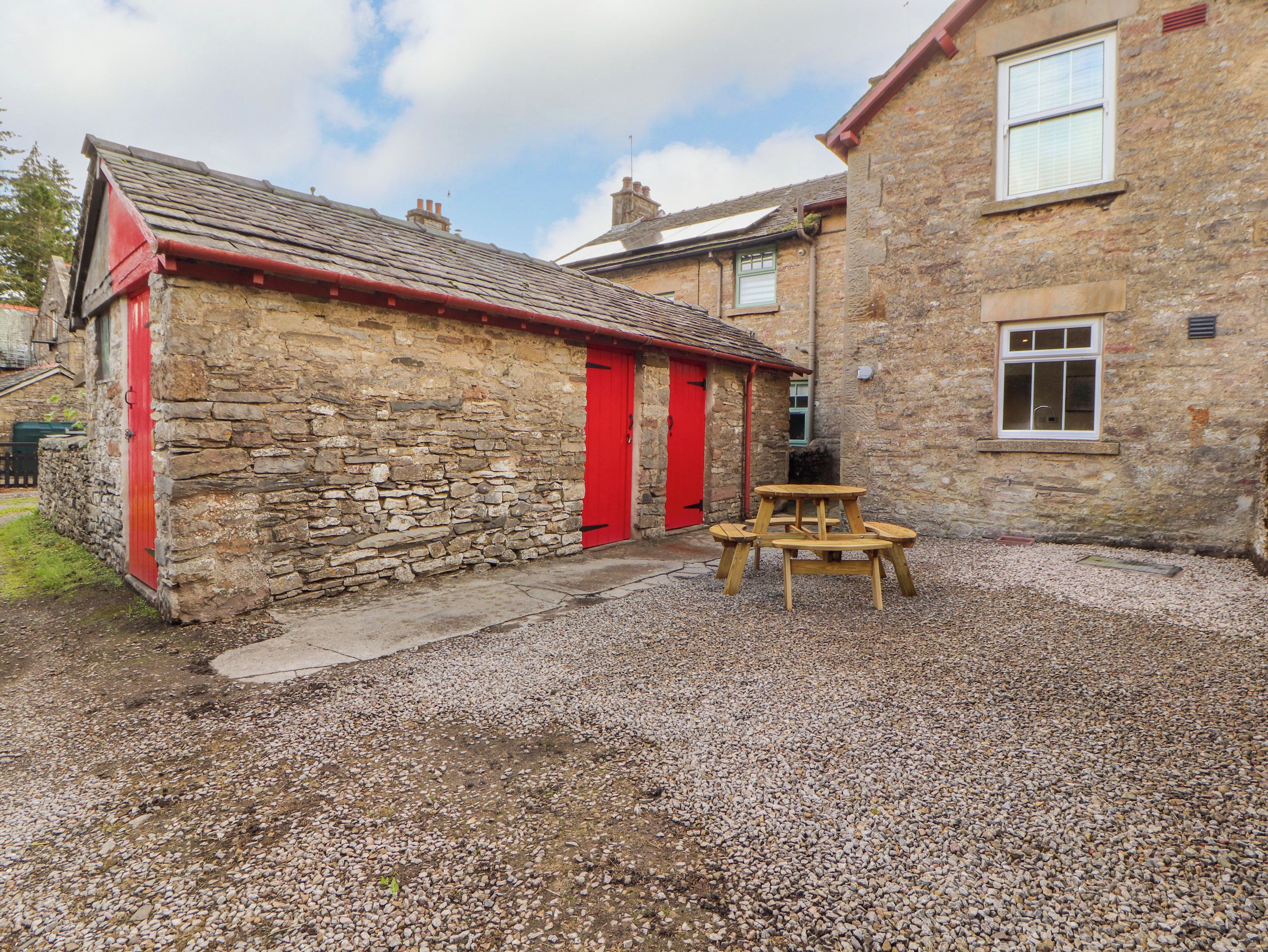 A stone building with a red door and a wooden bench in front.