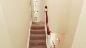 A carpeted staircase with a wooden handrail and a radiator on the wall. - East View (Kirkby Stephen)