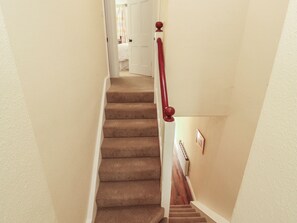 Ein Teppichbelag bedecktes Treppenhaus mit einer Holzhandläufe und einem Heizkörper an der Wand.