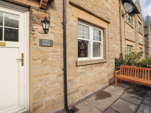 A stone building with a white door, a bench, and a sign reading 'EAST VIEW'. - East View (Kirkby Stephen)