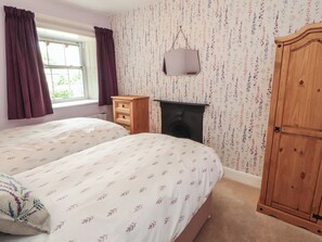 Ein Schlafzimmer mit zwei Betten, einem Schminktisch, einem Kamin und einem Kleiderschrank.