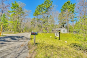 A rural road with a mailbox and a small cabin in the background.