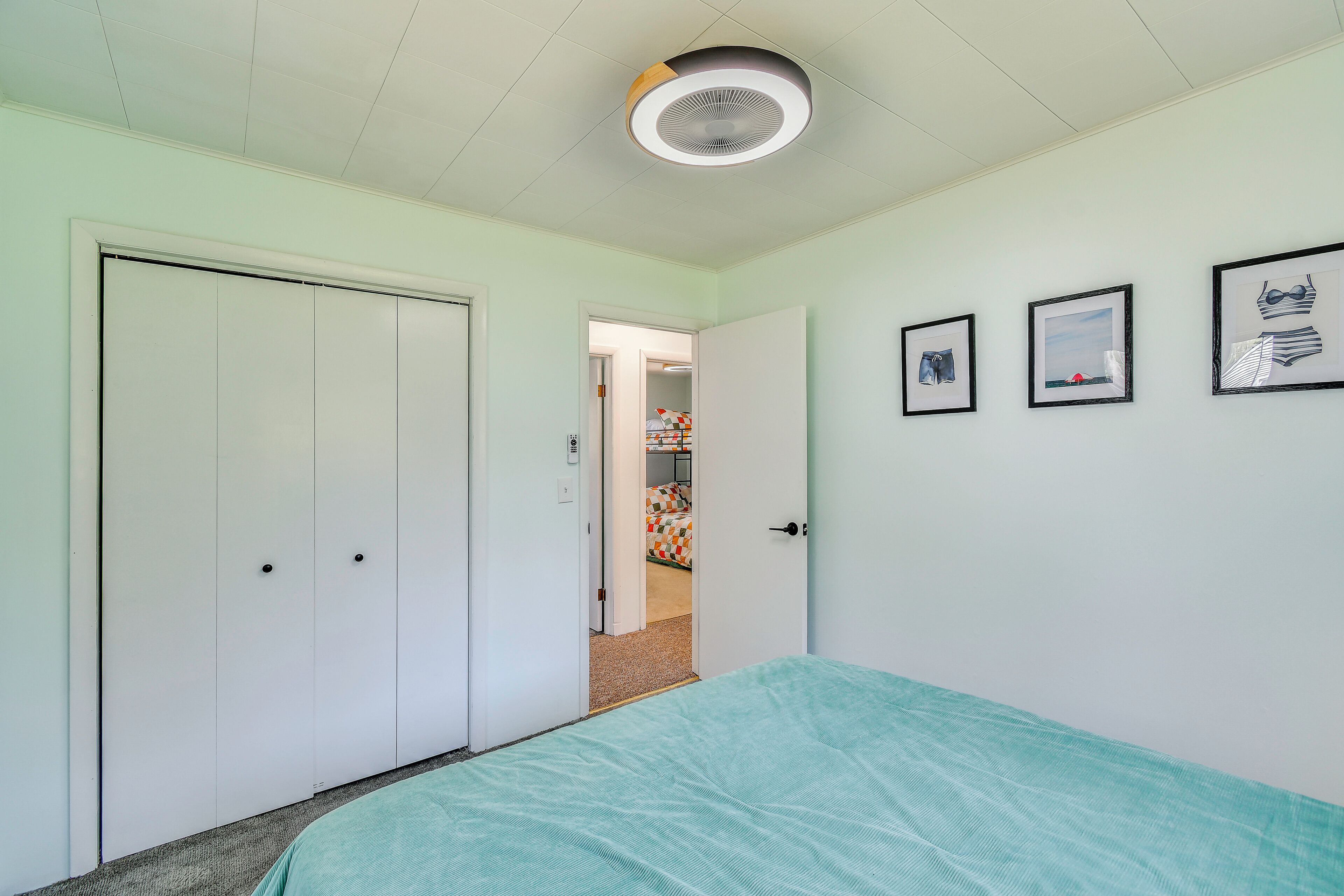 Un dormitorio con cama, armario, puerta y lámpara en el techo.