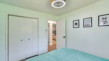 Un dormitorio con cama, armario, puerta y lámpara en el techo.