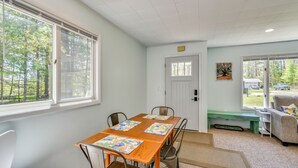 Una habitación con una mesa de madera, cuatro sillas, un banco, un sofá y una puerta que da al exterior.