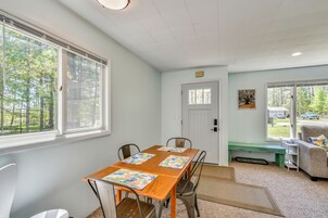 A room with a wooden table, four chairs, a bench, a sofa, and a door leading outside.