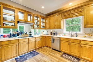 A kitchen with wooden cabinets, a stainless steel dishwasher, and a window providing natural light.