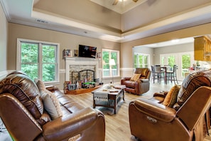 A spacious living room with leather sofas, a fireplace, a television, and a dining area.