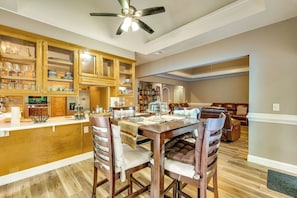 A spacious kitchen with wooden cabinets, a dining table with chairs, and a ceiling fan.