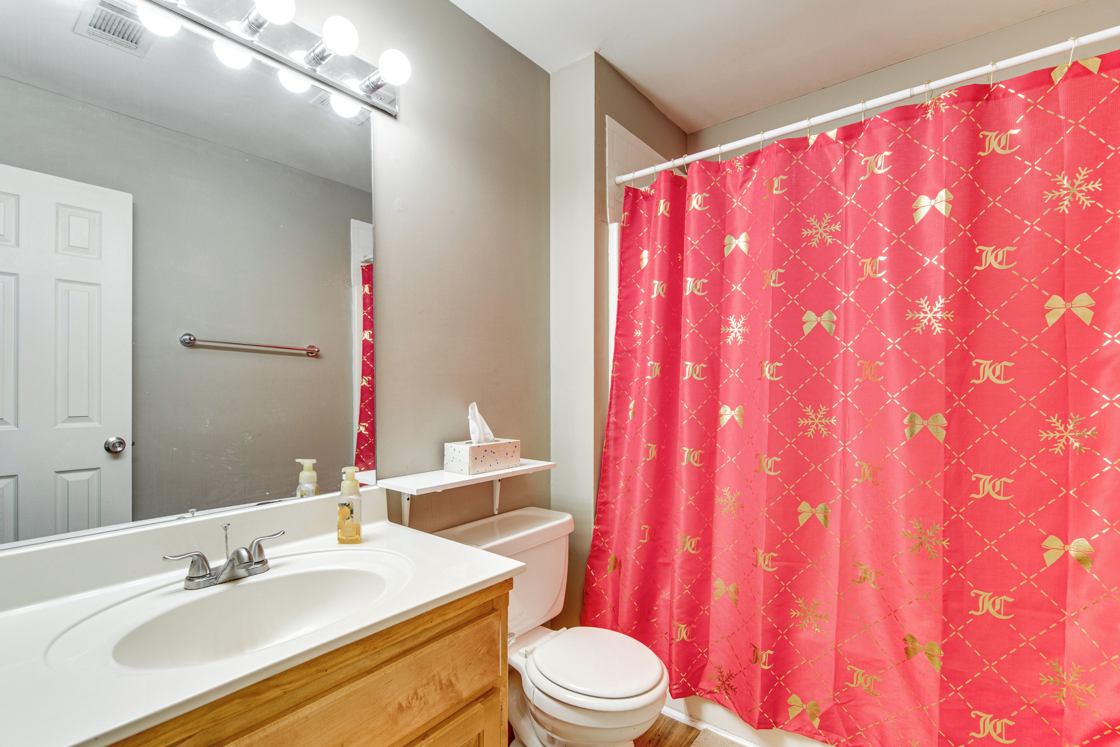Un baño con lavamanos, espejo y inodoro blancos.