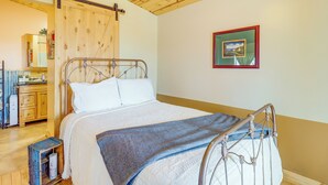 Een slaapkamer met een bed, houten plafond, een kleine tafel en een spiegel.