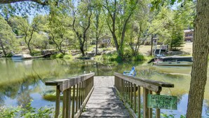 A wooden bridge leading to a house by a lake with a 'Welcome to the Lake' sign. - Cozy Cabin on the Cove, Large Deck & Private Dock (Groveland)