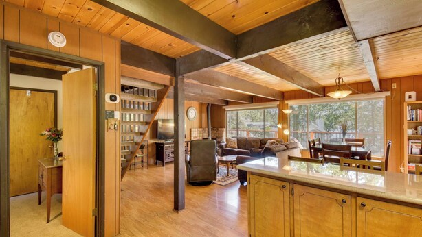 A spacious living area with a wooden ceiling, a kitchen with a large island, and a cozy seating area with a fireplace. - Cozy Cabin on the Cove, Large Deck & Private Dock (Groveland)
