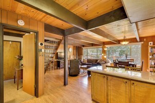 A spacious living area with a wooden ceiling, a kitchen with a large island, and a cozy seating area with a fireplace.