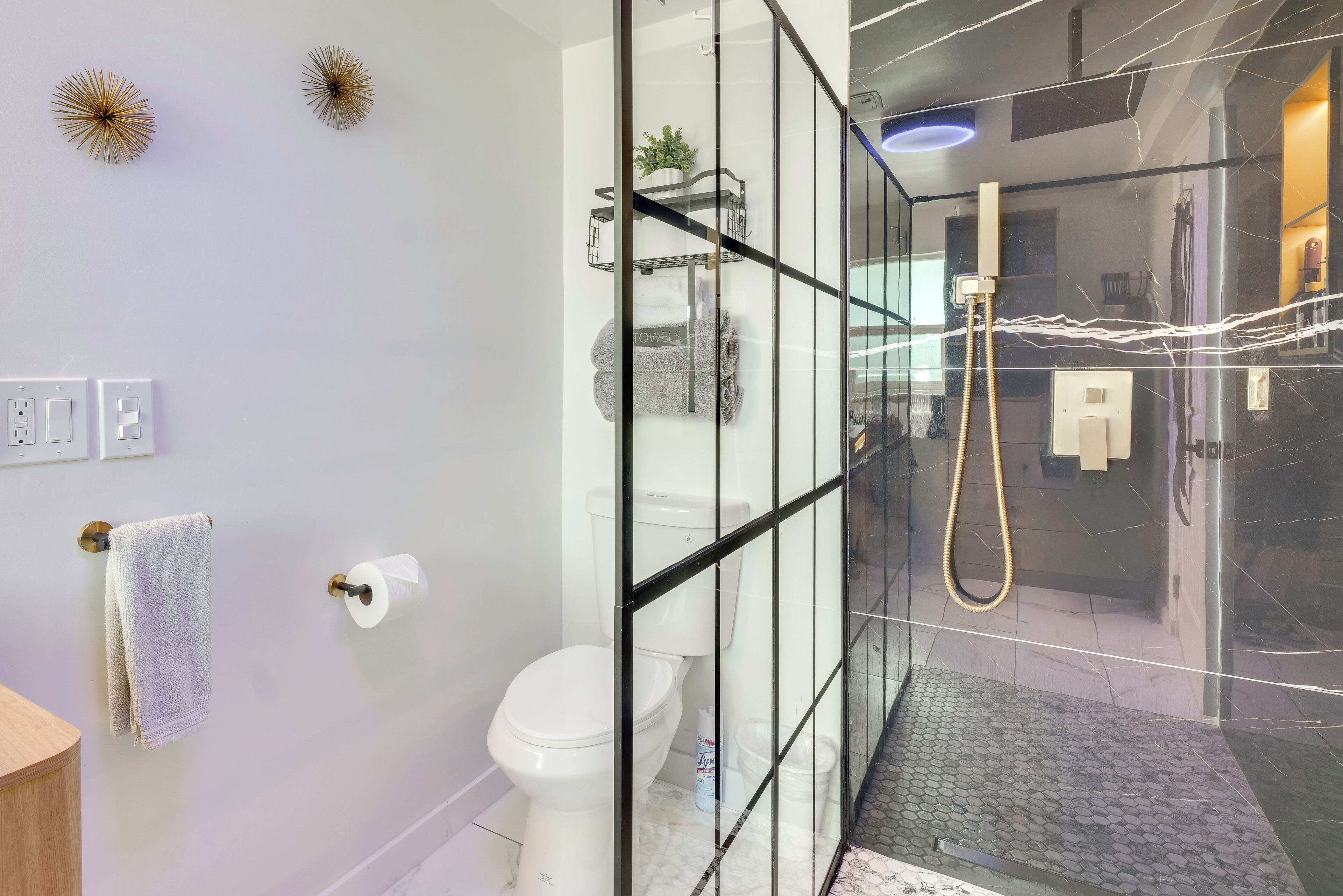 Une salle de bain moderne avec une douche à parois de verre, des toilettes, un porte-serviettes et un lavabo.