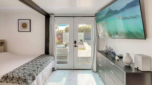 A bedroom with a bed, a TV, a framed picture, and a sliding door to a balcony. - Sleek Studio 4 Mi to Dtwn Phoenix: Pets Welcome! (Phoenix)