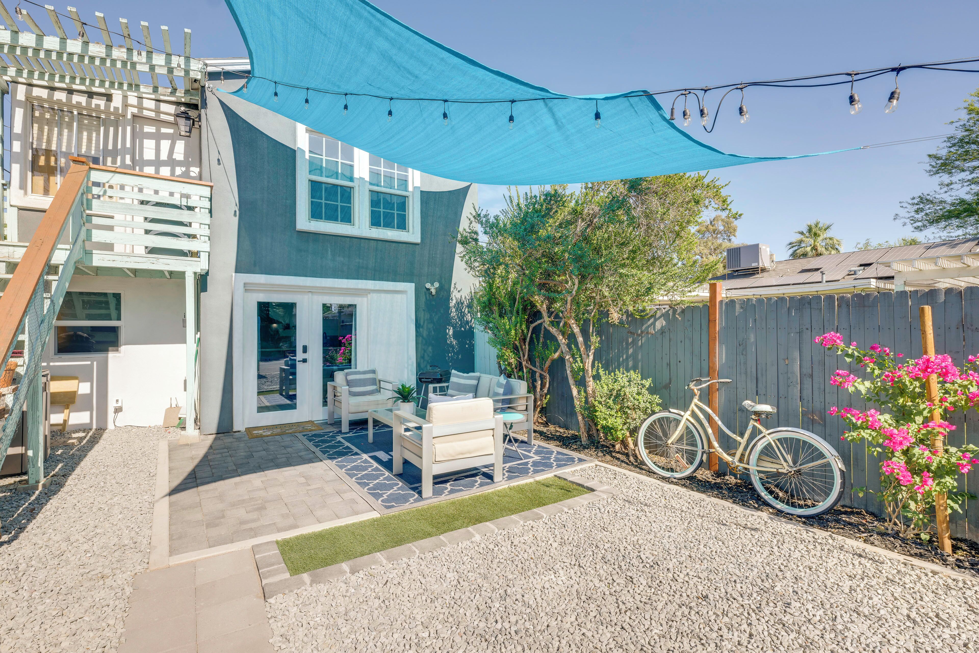 A backyard with a patio, outdoor seating, a bicycle, and a wooden fence.