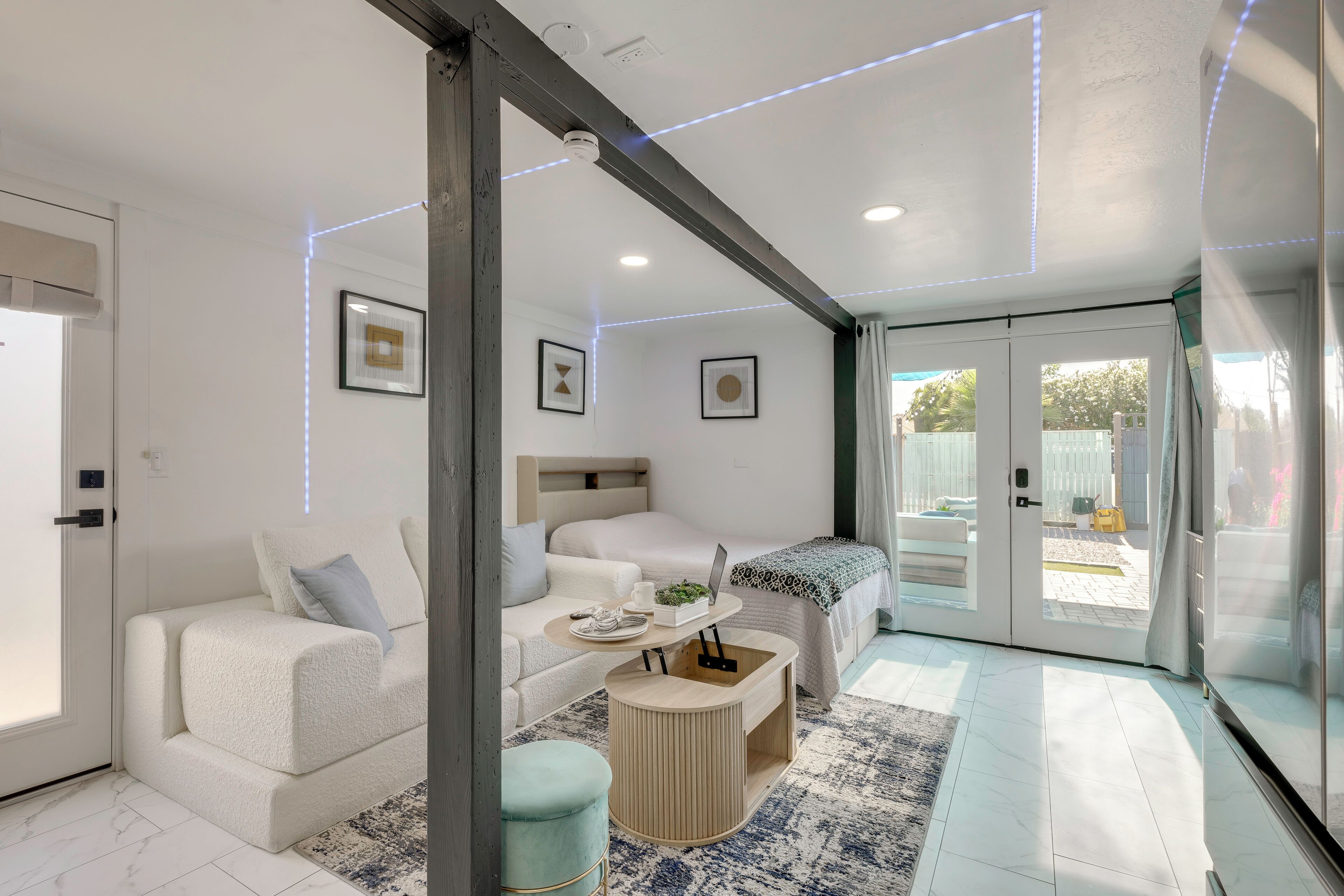 A modern living room with a sofa, a coffee table, and a bed.