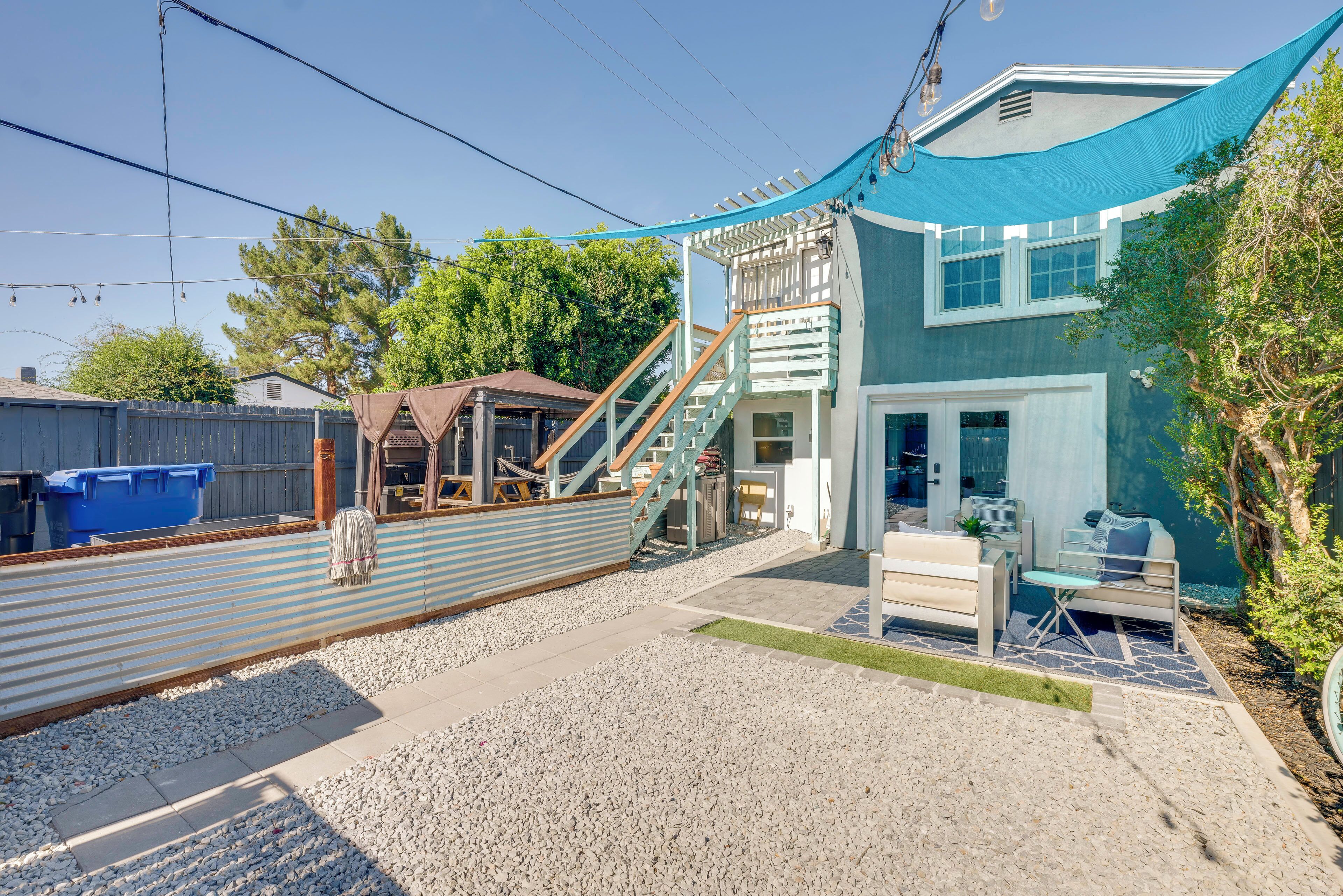 A two-story house with a covered patio, a wooden deck, and a small outdoor seating area.