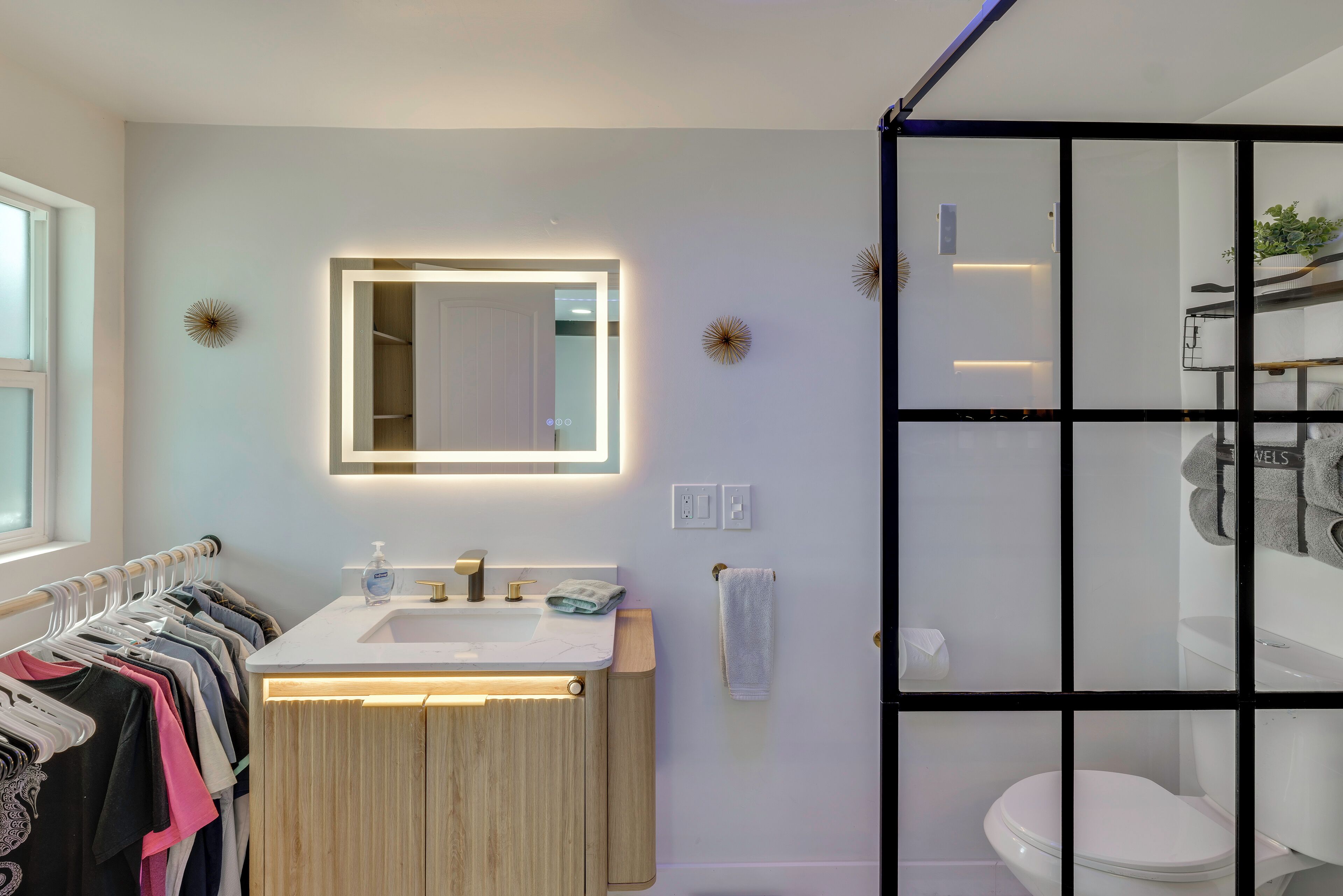 A modern bathroom with a wooden vanity, a large mirror, and a glass shower enclosure.