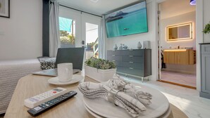 A modern hotel room with a bed, a desk with a laptop, a TV, and a bathroom visible. - Sleek Studio 4 Mi to Dtwn Phoenix: Pets Welcome! (Phoenix)