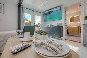 Ein modernes Hotelzimmer mit Bett, Schreibtisch, Laptop, Fernseher und angrenzendem Badezimmer.