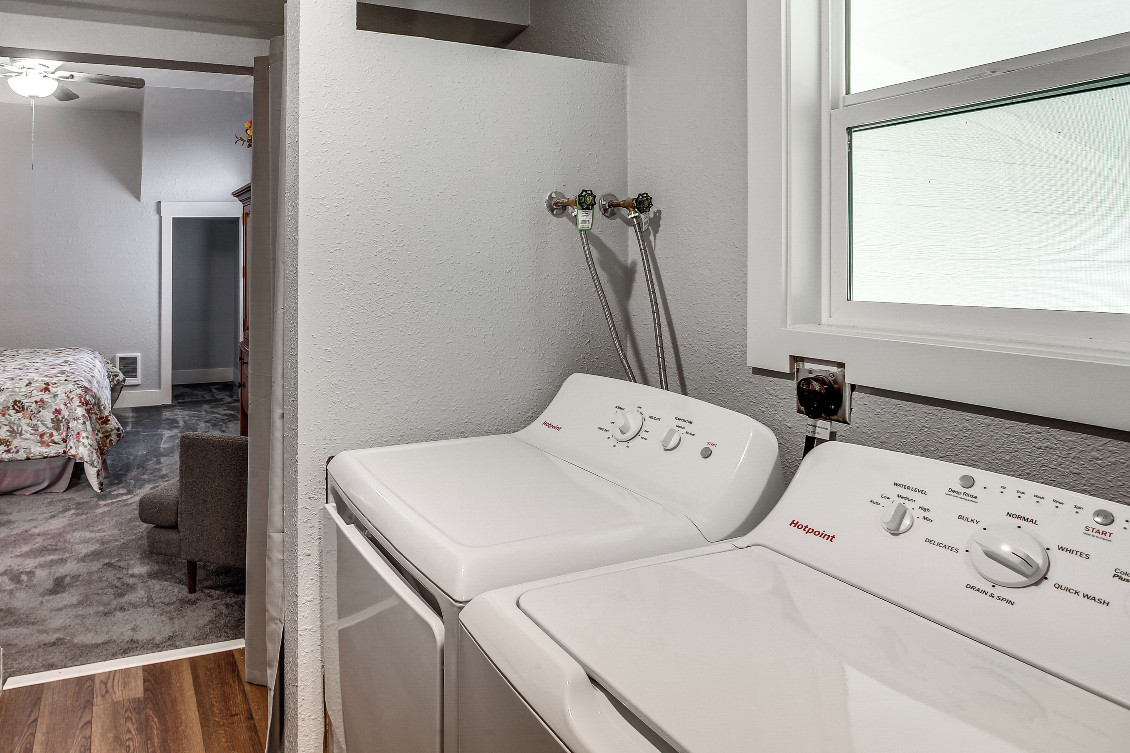 Ein Waschraum mit zwei weißen Frontlader-Waschmaschinen, einem Deckenventilator und einem Fenster.