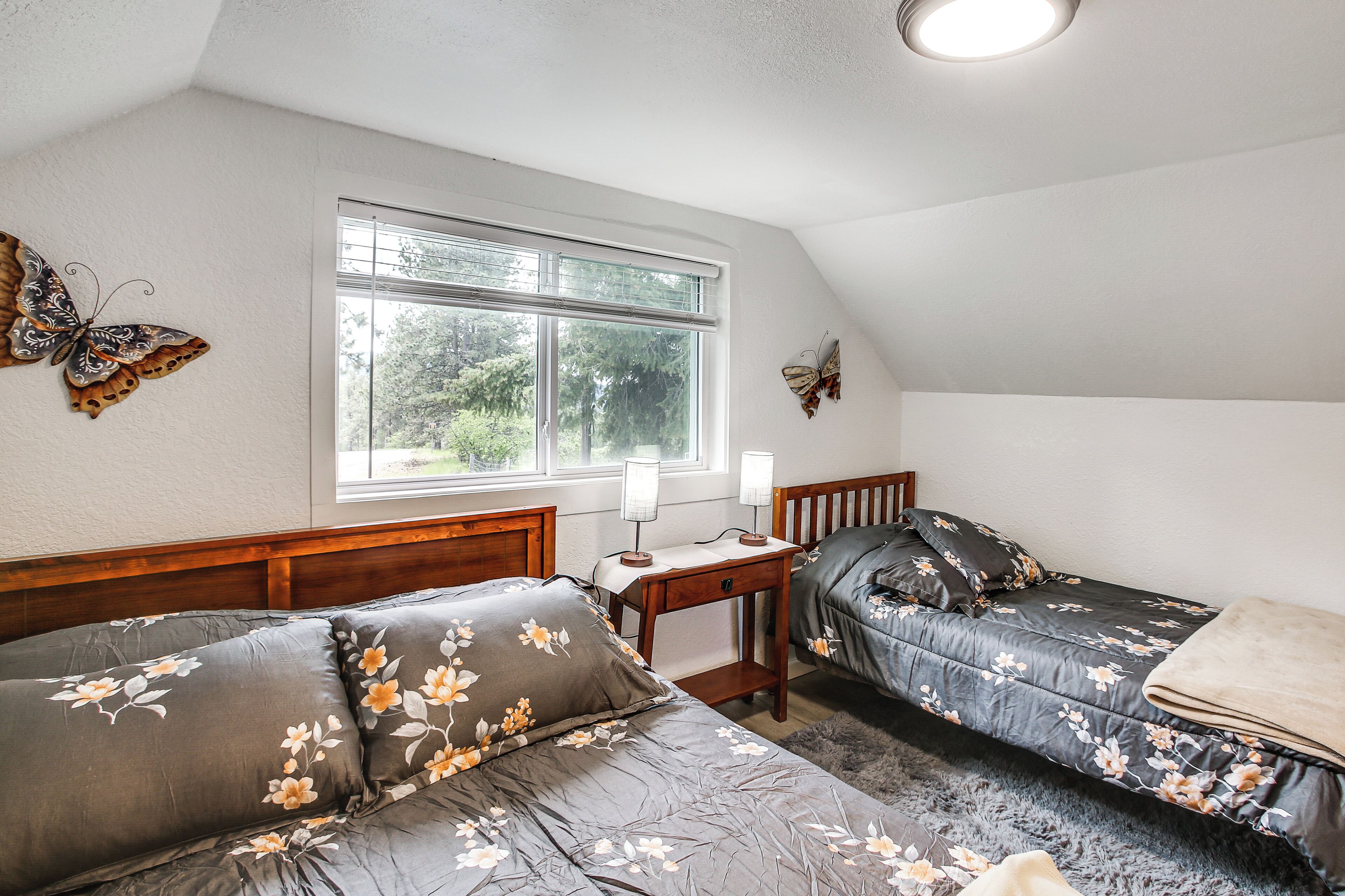 Un dormitorio con dos camas, una ventana y mariposas decorativas.