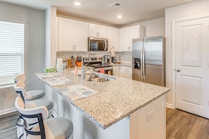 A kitchen with white cabinets, a granite countertop, a stainless steel refrigerator, and a built-in oven. - 2 Mi to Sea & Sand! Modern New Build in Surfside (Surfside Beach)