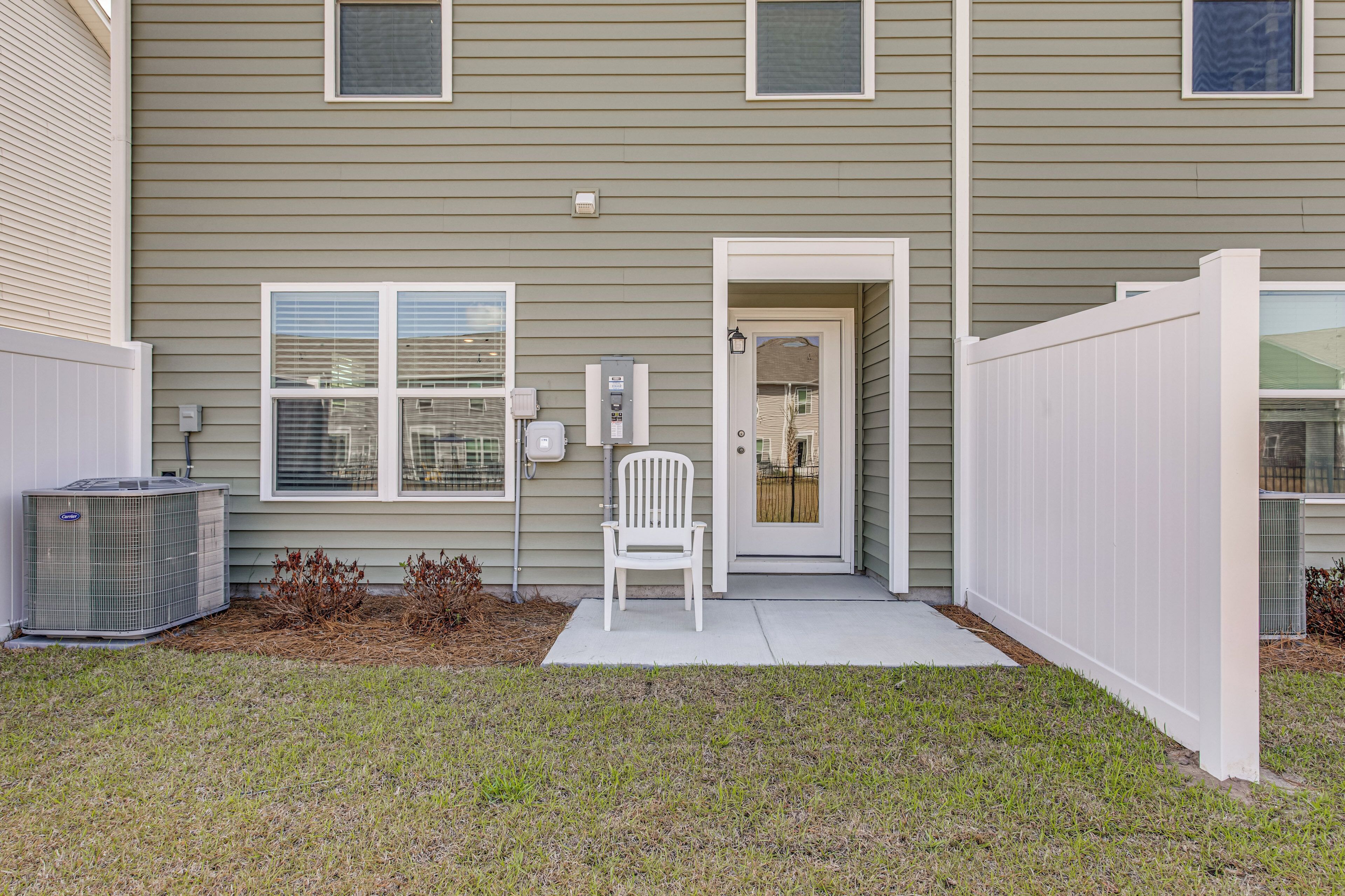 A residential building with a front door, a white chair outside, and an air conditioning unit.