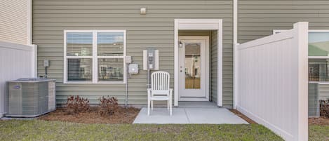 A residential building with a front door, a white chair outside, and an air conditioning unit.