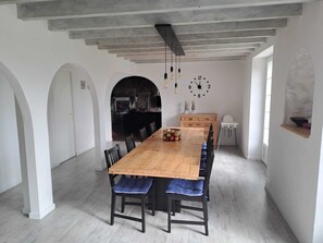 Un comedor con una larga mesa de madera, sillas negras y un reloj en la pared.