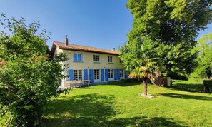 A two-story house with a tiled roof, a front porch, and a well-maintained lawn.