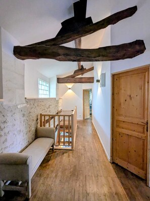 A room with a wooden staircase, a sofa, and a wooden door. - Charming holiday house with stunning view and heated swimming pool. (Palluaud)
