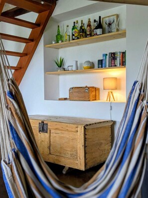 A hammock, wooden desk, shelves with books and bottles, and a lamp. - Charming holiday house with stunning view and heated swimming pool. (Palluaud)