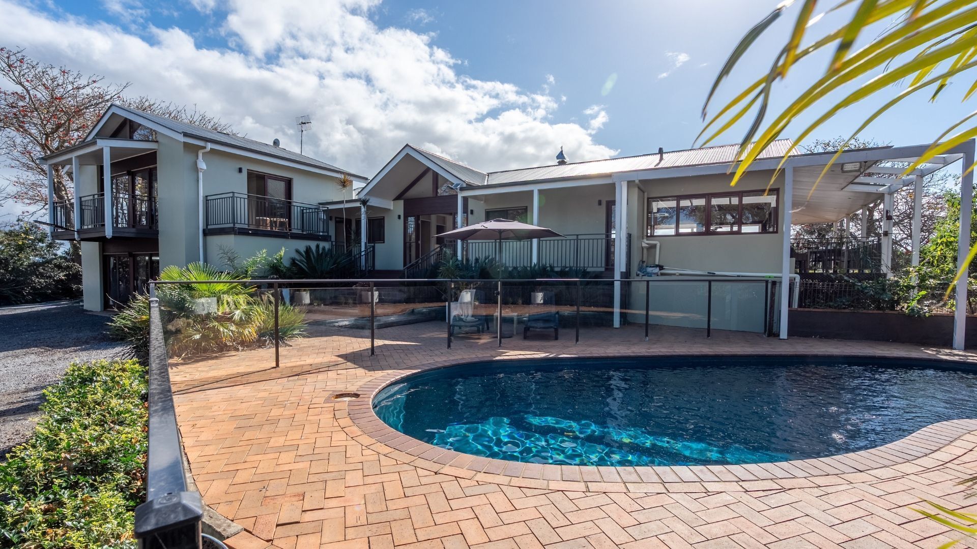 A two-story house with a swimming pool, a covered patio, and a fenced garden area.