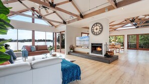 Uma sala de estar espaçosa com lareira, um relógio grande e vista para o exterior.