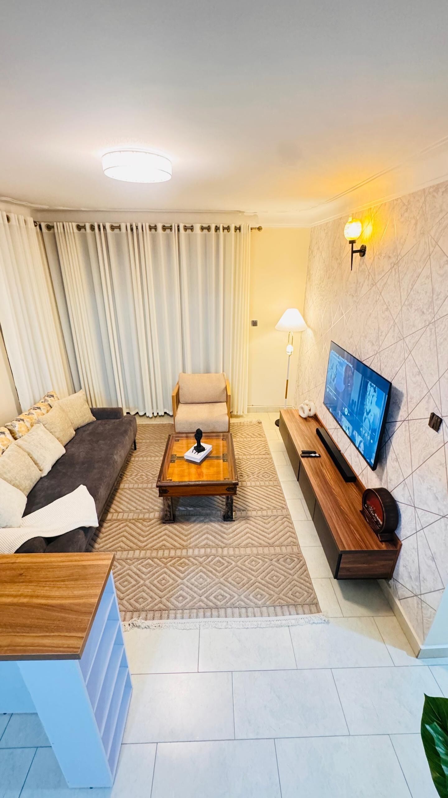 Una sala moderna con sofá, sillón, mesa de centro, televisor y una alfombra estampada.
