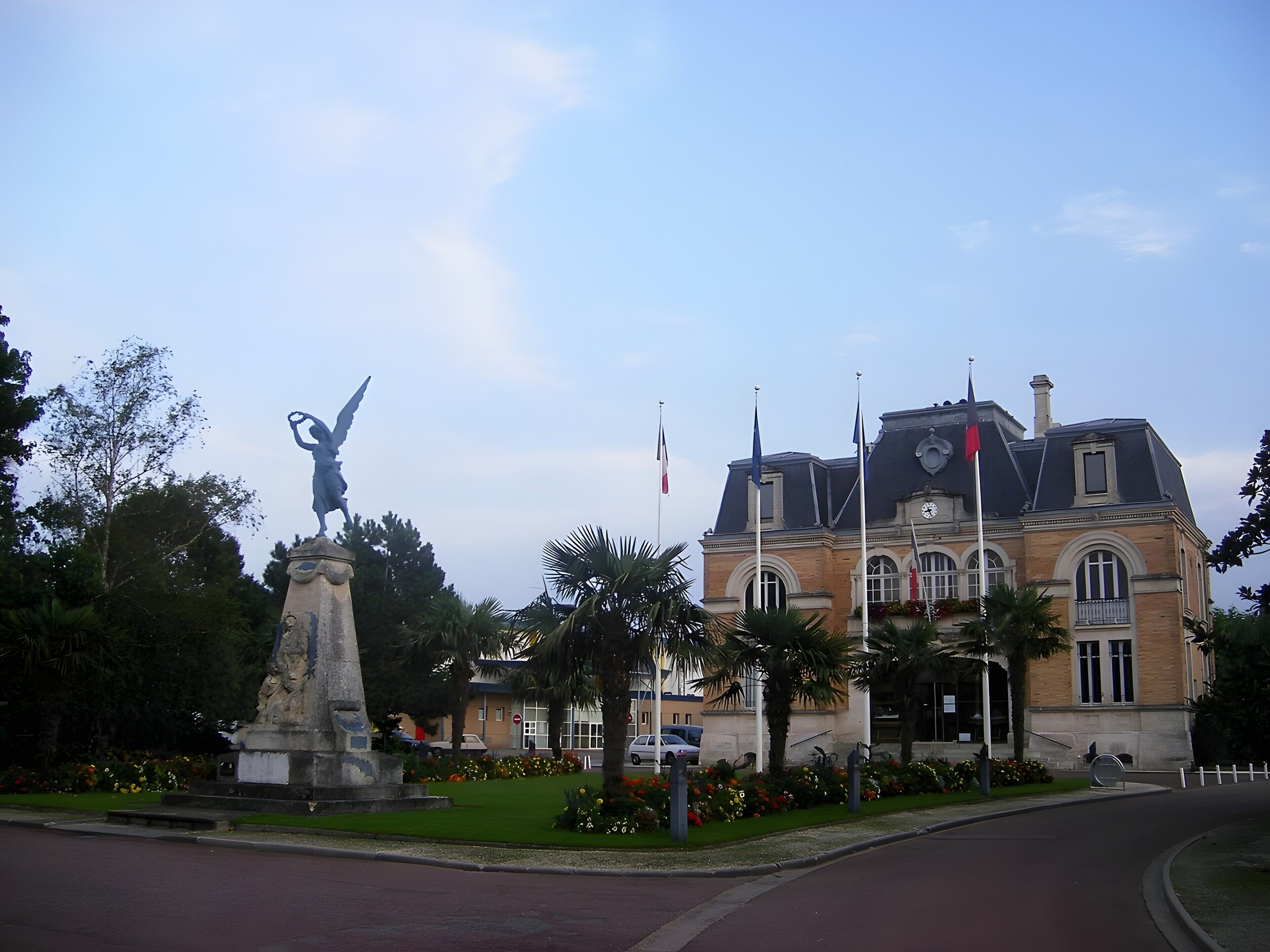 A building with a classical architectural style, featuring a prominent statue in front.