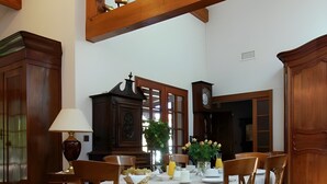 A dining room with a round table, chairs, a chandelier, wooden beams, and a ship model. - Guest Room "Les Pins" with Shared Terrace, Wi-Fi, and Air Conditioning (Gujan-Mestras)