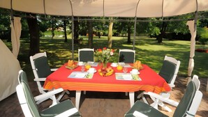 A tented dining area with a table set for four, surrounded by chairs, and a canopy overhead. - Guest Room "Les Pins" with Shared Terrace, Wi-Fi, and Air Conditioning (Gujan-Mestras)