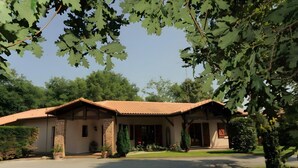A two-story building with a tiled roof, a brick facade, and a front entrance. - Guest Room "Les Pins" with Shared Terrace, Wi-Fi, and Air Conditioning (Gujan-Mestras)