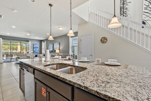 Eine moderne Küche mit Granit Arbeitsplatten, Edelstahlgeräten und Pendelleuchten.