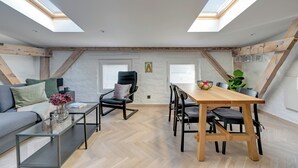 Quarto estilo loft com área de jantar, sofá e mesa de centro de vidro.