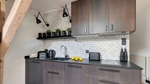 Uma cozinha moderna com armários de madeira escura, bancada preta e painel de backsplash de tijolos brancos.